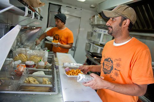 Pratik Jani (right) and Farhan Ahmed prepare freshly made Indian food orders inside the Masala Fresh truck at the Atlanta Food Truck Park & Market off of Howell Mill Road on Saturday, May 11, 2013. 