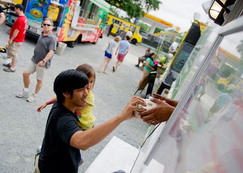 Piya Sarapala (center) holds his daughter Thalia as he picks up food from Masala Fresh truck at the Atlanta Food Truck Park & Market off of Howell Mill Road on Saturday, May 11, 2013. 