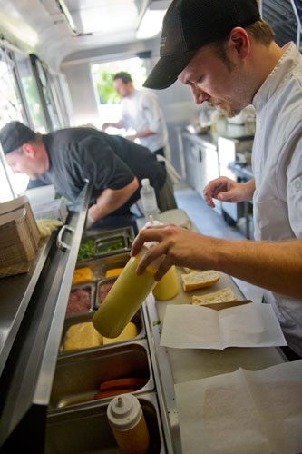Tyler Lee (right), Bill Wooldridge and Justin Ballard share the 8x18 foot space inside the Happy Belly food truck as they prepare food orders at Taylor-Brawner Park in Smyrna on Tuesday, May 14, 2013. 