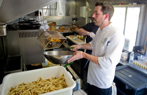 Justin Ballard prepares an order of french fries inside the Happy Belly food truck at Taylor-Brawner Park in Smyrna on Tuesday, May 14, 2013.
