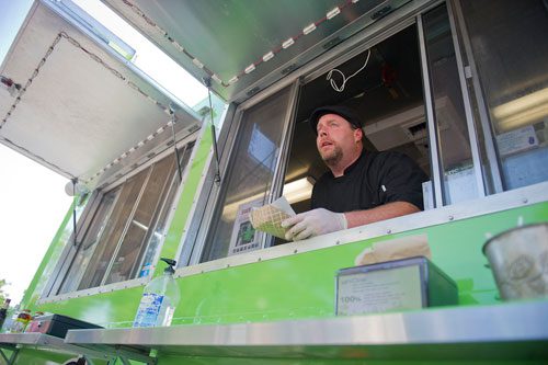 Bill Wooldridge calls out people's names as he places food on the counter from the window of the Happy Belly food truck at Taylor-Brawner Park in Smyrna on Tuesday, May 14, 2013. 
