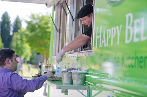 Christian Cali (left) picks up his food order from  Bill Wooldridge as he leans out of the window of the Happy Belly food truck at Taylor-Brawner Park in Smyrna on Tuesday, May 14, 2013. 