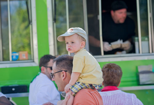 Brecken Heath (center) sits on his father Kevin's shoulders as they wait for Bill Wooldridge (top right) to call out their names to pick up food from the Happy Belly food truck at Taylor-Brawner Park in Smyrna on Tuesday, May 14, 2013. 