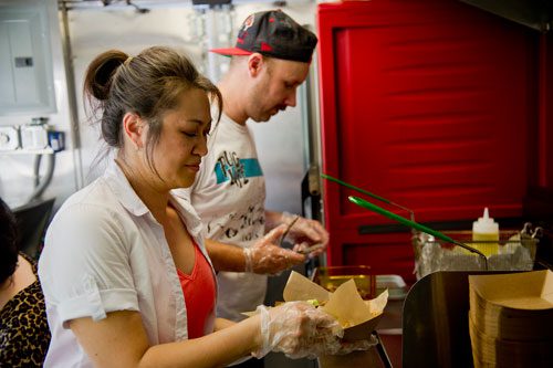 Nomie Truong (left) and Drew Moody prepare food orders inside the Viet-Nomie's food truck in Roswell on Thursday, May 16, 2013. 