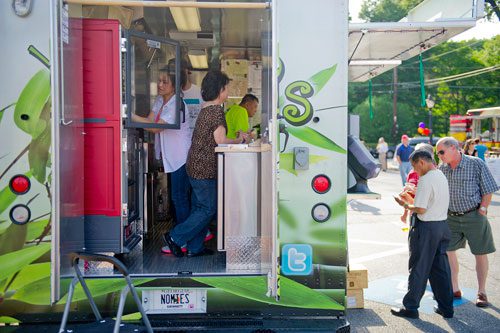 Nomie Truong (left), her mother Thuy Tran and husband Paul Truong prepare food orders as her father Dominique Tran helps Tom Burleson look over the menu from the Viet-Nomie's food truck in Roswell on Thursday, May 16, 2013.
