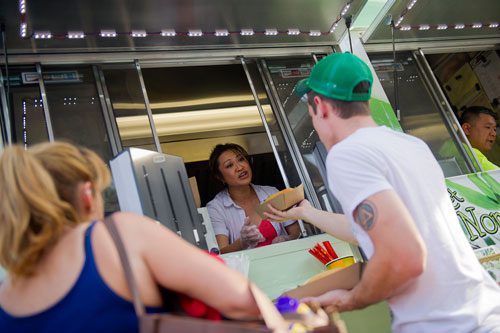 Nomie Truong (center) hands a food order to Ryan Young and Tanya Frazier from the Viet-Nomie's food truck in Roswell on Thursday, May 16, 2013. 