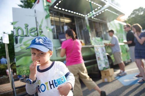 Banks Vessels (left) eats a jazzi roll as people order from the Viet-Nomie's food truck in Roswell on Thursday, May 16, 2013. 