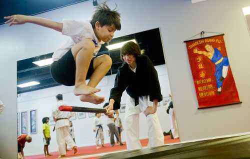 Daniel Marconi (left) jumps over a stick held by Sam Eppstein during Kung Fu Camp at Highland Martial Arts in the Virginia Highlands neighborhood of Atlanta on Wednesday, June 12, 2013. 