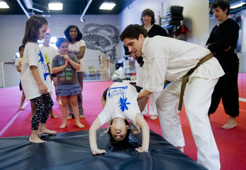 Daniel Marconi (center) falls into a backbend with the help of David Drake (right) as Alessandra Marconi (left) waits for her turn to try during Kung Fu Camp at Highland Martial Arts in the Virginia Highlands neighborhood of Atlanta on Wednesday, June 12, 2013. 