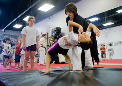 Sophia Huynh (right) falls into a backbend with the help of Sam Eppstein as Carly G. Pilgar waits for her turn to try during Kung Fu Camp at Highland Martial Arts in the Virginia Highlands neighborhood of Atlanta on Wednesday, June 12, 2013. 
