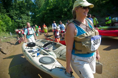 Jen Griffith (right) carries her two kayaks towards the edge of the water with the help of her husband Kevin before they start the Back to the Chattahoochee River Race & Festival in Roswell on Saturday, June 15, 2013.