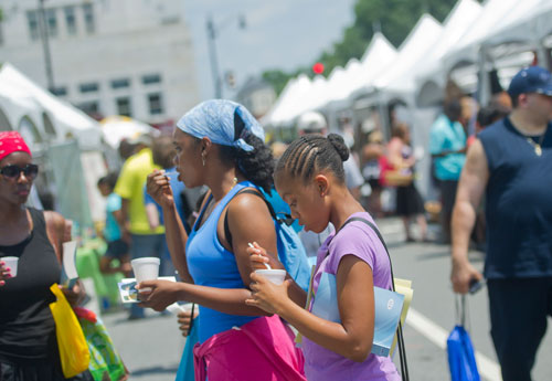 Niara Minnifields (center) and her mother Colette taste some of the food available during the Cobb NAACP Juneteenth Celebration in Marietta Square on Saturday, June 15, 2013. 