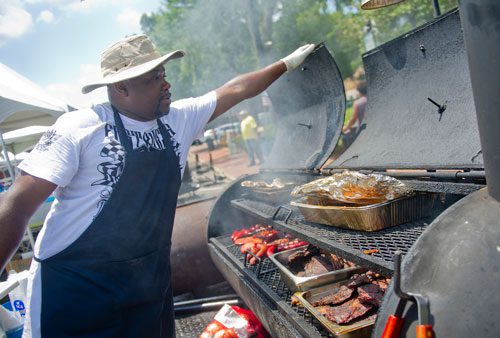 Brent Echols checks on the meat cooking in his smoker during the Cobb NAACP Juneteenth Celebration in Marietta Square on Saturday, June 15, 2013.