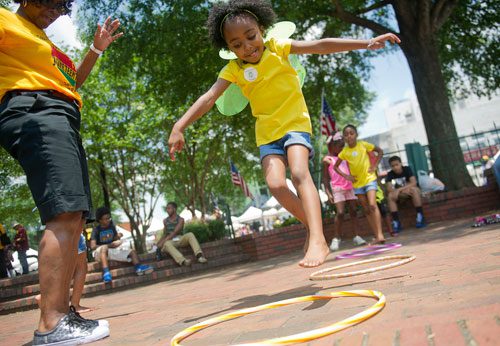 Nia Caudle (center) jumps into the center of a hoop as she plays games during the Cobb NAACP Juneteenth Celebration in Marietta Square on Saturday, June 15, 2013. 