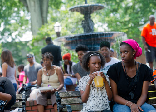 Isha Faye (right) and Oumie Faye sit on a bench as they watch the performances during the Cobb NAACP Juneteenth Celebration in Marietta Square on Saturday, June 15, 2013. 