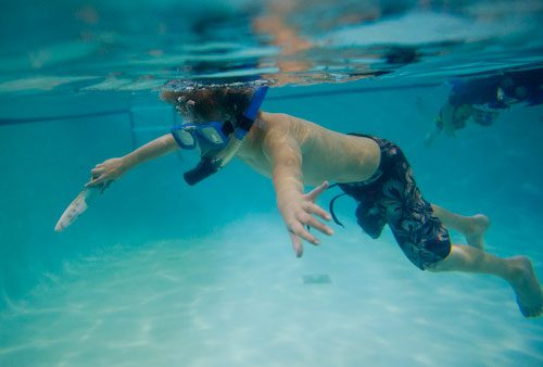 Kai Norton (center) floats through the water wearing snorkeling gear as Itay Shani swims by during H2O Zone Camp at SeaVentures in Alpharetta on Thursday, June 6, 2013. 