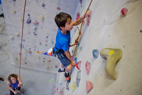 Ben Singer (right) pulls himself up a rock wall as Libbi Gilson belays him during climbing camp at the Stone Summit Climbing Center in Atlanta on Thursday, June 6, 2013. 