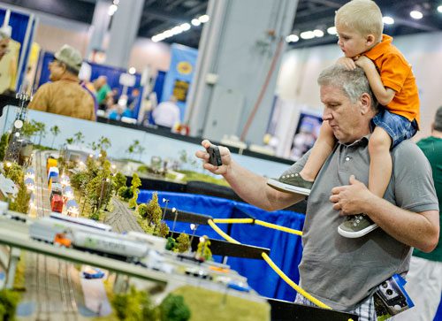 Ralph Knaute (left) holds his grandson Levi Clark on his shoulders as he takes a photograph of one of the displays during the 23rd Annual Nation Train Show at the Cobb Galleria Centre in Atlanta on Saturday, July 20, 2013. 