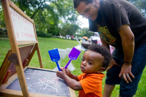 Otis Stone (left) plays with an antique chalk board as his father Nate stands over him at the Town Meets Country pop up market at the Wren's Nest in Atlanta on Sunday, July 28, 2013. 