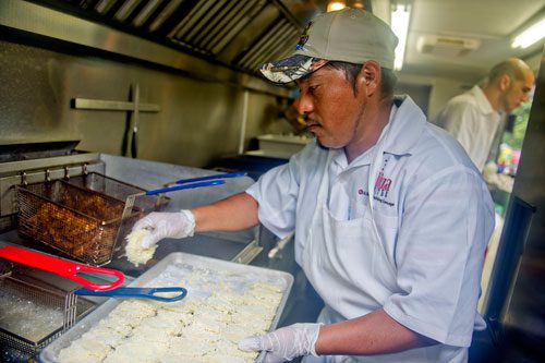 Alejandro Camacho (center) prepares food inside the Ibiza Bites truck as Miguel Morales takes orders from the window during the Atlanta Street Food Festival at Piedmont Park on Saturday, July 13, 2013. 
