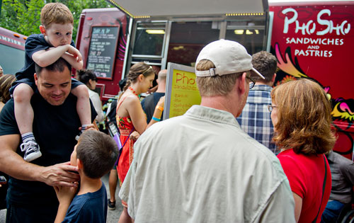 Jaxon McLean sits on his father David's shoulders as he messes with his brother Caden while waiting in line to pick up their food from the Pho Sho truck during the Atlanta Street Food Festival at Piedmont Park on Saturday, July 13, 2013.