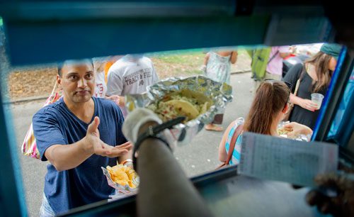 Anand Goel reaches for his order from the Texas Tacos truck during the Atlanta Street Food Festival at Piedmont Park on Saturday, July 13, 2013. 
