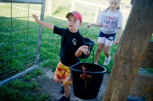 Chase Veitch (left) and Noele Dillingham carry buckets of food to feed the animals during summer camp at Rancho Alegre Farm in Dacula on Friday, June 14, 2013. 