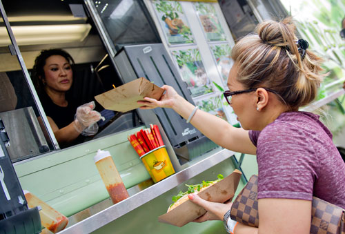 Monica Eung (right) grabs a tray of food from Nomie Truong during the Atlanta Street Food Festival at Piedmont Park on Saturday, July 13, 2013. 