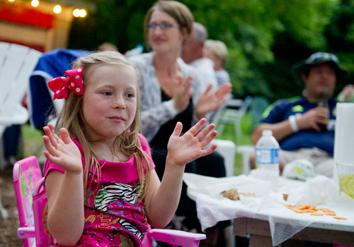 Hayden Wolff (left) claps as she sits with her family while they listen to the band Waller perform on stage at Matilda's Under the Pines in Alpharetta on Saturday, July 13, 2013. 
