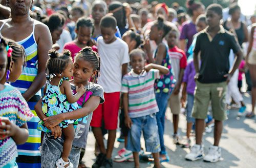 Kimberly Zachary (left) is held by her sister Keyshuana as they stand in line to receive school supplies during the Hosea Feed the Hungry & Homeless' 8th Annual Back to School Jamboree at Turner Field's Blue Lot in Atlanta on Saturday, July 20, 2013.