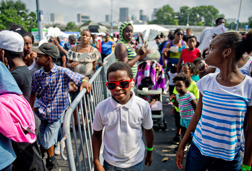 Kevin Pitts (center) and Modeline Romelus stand in line as they wait to receive school supplies during the Hosea Feed the Hungry & Homeless' 8th Annual Back to School Jamboree at Turner Field's Blue Lot in Atlanta on Saturday, July 20, 2013. 