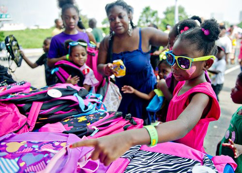 Justice Meadows (right) picks out the perfect backpack with her family during the Hosea Feed the Hungry & Homeless' 8th Annual Back to School Jamboree at Turner Field's Blue Lot in Atlanta on Saturday, July 20, 2013. 