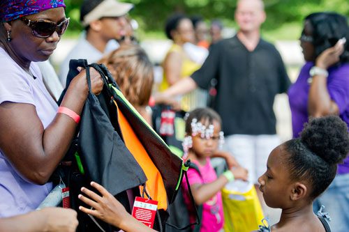 Chona Gullett (left) holds a handful of backpacks as Ka'Nya Wallace choses one during the Hosea Feed the Hungry & Homeless' 8th Annual Back to School Jamboree at Turner Field's Blue Lot in Atlanta on Saturday, July 20, 2013. 