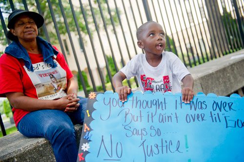 Kamarion Newsome (right) waves a sign as he stands next to Susie Kier before the start of the Trayvon Martin Rally at the Georgia State Capitol in Atlanta on Sunday, July 28, 2013. 