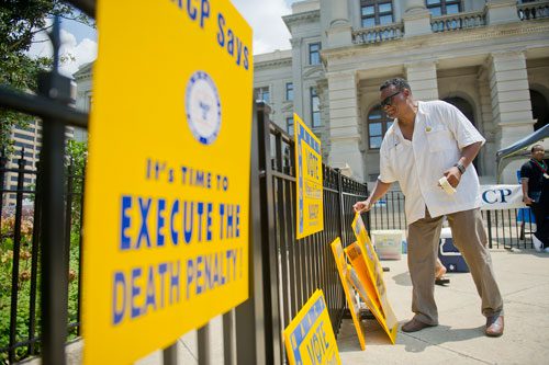 Dr. Quincy Harris puts up signs in front of the capitol building before the start of the Trayvon Martin Rally at the Georgia State Capitol in Atlanta on Sunday, July 28, 2013. 
