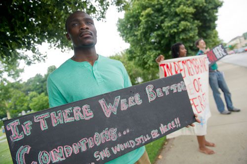 Marcus Bracey (left), Rabiah Elisa and Robert Feria hold signs voicing workers' rights during the We Are Here Rally for Respect in Rememberance of Teresa Weaver Pickard at Piedmont Park in Atlanta on Wednesday, June 26, 2013. 