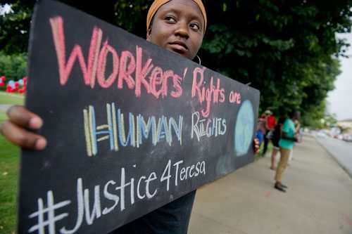 Kendra Williams holds a sign voicing workers' rights during the We Are Here Rally for Respect in Rememberance of Teresa Weaver Pickard at Piedmont Park in Atlanta on Wednesday, June 26, 2013. 