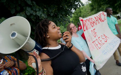 Shapel LaBorde (left) chants to passersby using a bullhorn as Kathy Acker and Marcus Bracey hold up a sign during the We Are Here Rally for Respect in Rememberance of Teresa Weaver Pickard at Piedmont Park in Atlanta on Wednesday, June 26, 2013. 