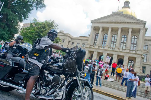 Roland Cheeks (left) parks his bike on Washington Street in front of the capitol building during the Trayvon Martin Rally at the Georgia State Capitol in Atlanta on Sunday, July 28, 2013. 