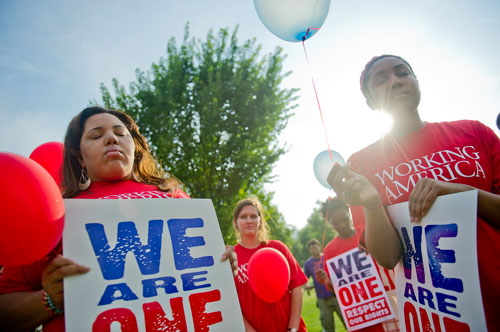 Nia James (left) and Courtnee Brinker hold balloons and signs as they observe a moment of silence as part of the We Are Here Rally for Respect in Rememberance of Teresa Weaver Pickard at Piedmont Park in Atlanta on Wednesday, June 26, 2013. 