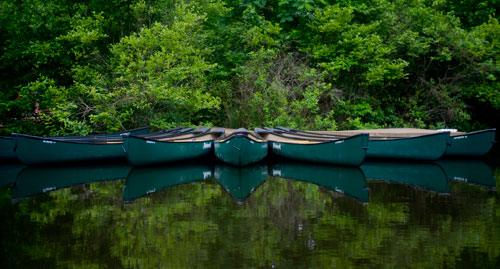 Empty canoes are reflected in the water of one of three ponds at the Chattahoochee Nature Center in Roswell on Wednesday, June 5, 2013.