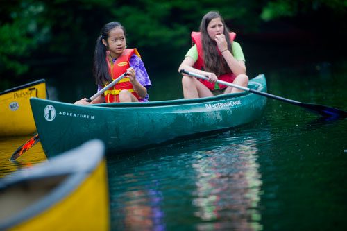 Mariette Brannan (left) and Caroline Shewmaker manuever their canoe on one of the three ponds at the Chattahoochee Nature Center in Roswell during Camp Kingfisher on Wednesday, June 5, 2013.