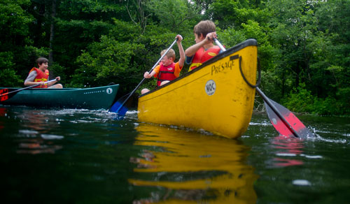 Ethan Grimes (right) and Jacob Evans paddle their canoe away from Leo Nayshtut (left) on one of the three ponds at the Chattahoochee Nature Center in Roswell during Camp Kingfisher on Wednesday, June 5, 2013.
