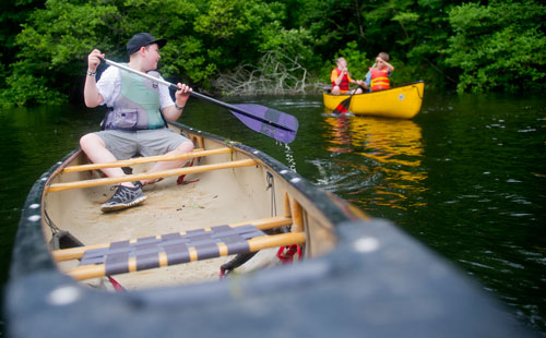 Patrick Fletcher (left) paddles his canoe on one of the three ponds at the Chattahoochee Nature Center in Roswell as he looks back at Jacob Evans and Ethan Grimes during Camp Kingfisher on Wednesday, June 5, 2013.