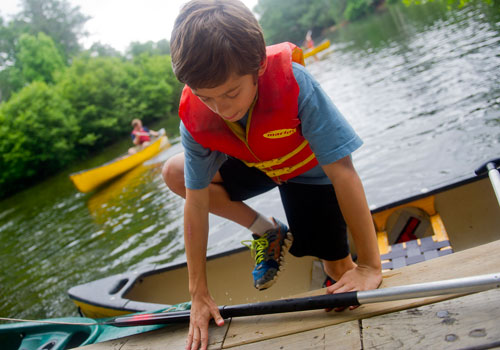 Ethan Grimes climbs out of his canoe and onto the dock after paddling in one of the three ponds during Camp Kingfisher at the Chattahoochee Nature Center in Roswell on Wednesday, June 5, 2013. 