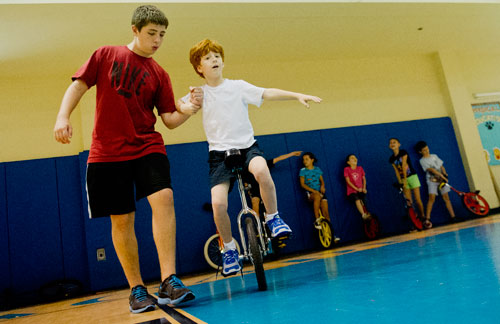 Jack Dwyer (left) helps steady Adam Schultz as he learns to ride a unicycle during Circus Summer Camp at Davis Academy in Dunwoody on Wednesday, July 10, 2013.
