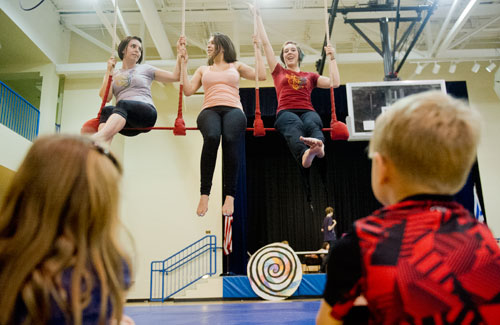 Instructors Katie Martin (left), Allie Goodman and Liz Ramsay demonstrate a triple trapeze act to campers during Circus Summer Camp at Davis Academy in Dunwoody on Wednesday, July 10, 2013.