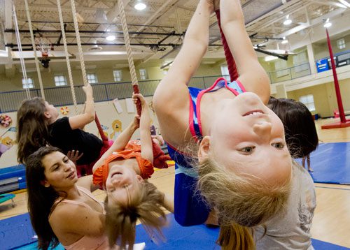 Cara Oswalt (right) hangs from a triple trapeze as junior counselor Allie Goodman helps position Susan Price during Circus Summer Camp at Davis Academy in Dunwoody on Wednesday, July 10, 2013. 