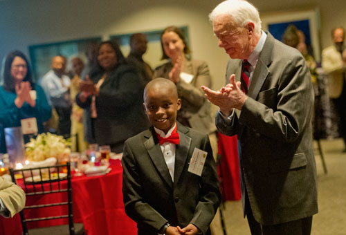 Zaqary Asuamah (left) gets a standing ovation led by former President Jimmy Carter after reciting Dr. Martin Luther King Jr.'s famous I Have a Dream speech during America's Sunday Supper at the Carter Center in Atlanta on Sunday, August 11, 2013.