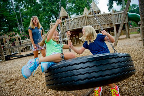 Julie Craig (left) pushes her daughter Kylie and her friend Anna Hewitt on a tire swing at the Wacky World Playground at Wills Park in Alpharetta on Thursday, August 8, 2013. 